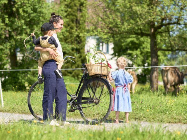 Frau mit Fahrrad, Einkaufskorb mit Lebensmitteln und Kindern