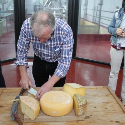 Mann beim zerschneiden des Käselaibes